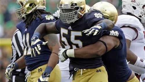Notre Dame linebacker Prince Shembo (55) celebrates as he's hugged by teammate Stephon Tuitt after a tackle for a loss against Temple during the first half of an NCAA college football game in South Bend, Ind., Saturday, Aug. 31, 2013. (AP Photo/Michael Conroy)