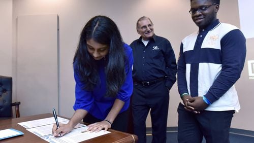 Former student interns Elizabeth Karivelil and Patrick Aghadiuno, both GSMST students, sign an “application note” document as Dr. Simon Yunes (center), senior application scientist at Micromeritics Instrument Corporation. looks on Thursday, April 19, 2018. Micromeritics, a 55-year-old Norcross-based global manufacturer of scientific instruments, has had a longtime commitment to Gwinnett County Public Schools and student development with an internship program. Students this year helped publish a scientific paper on groundbreaking research to help the industry become more efficient in a manufacturing process. HYOSUB SHIN / HSHIN@AJC.COM
