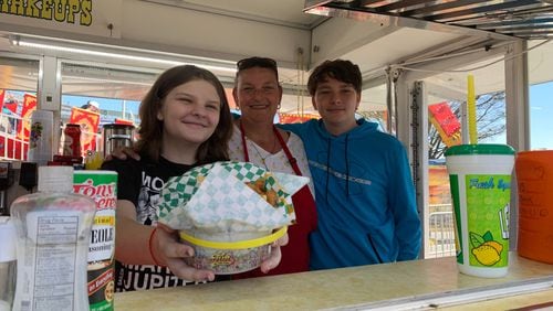 It’s a family affair as Anna Young, 12, her mother, June, and brother Alex, 15, serve up some fries with chili at the family’s booth, Young’s Famous Chicken n Fries. Photo by Grady McGill