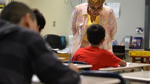 Gloria Watson helps an eighth-grade student at Tucker Middle School with a class assignment. Watson, a retired teacher, was substituting at the DeKalb County middle school when this picture was taken in 2015. District records indicate DeKalb’s school system doesn’t find a substitute for every time a teacher is absent. BRANT SANDERLIN/BSANDERLIN@AJC.COM