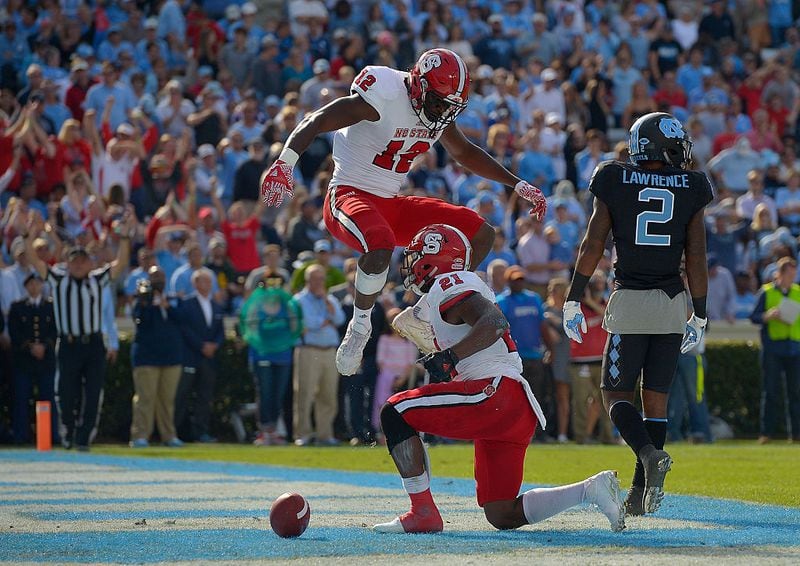 CHAPEL HILL, NC - NOVEMBER 25: Stephen Louis #12 and Matthew Dayes #21 of the North Carolina State Wolfpack celebrate after Dayes' touchdown against the North Carolina Tar Heels during their game at Kenan Stadium on November 25, 2016 in Chapel Hill, North Carolina.  (Photo by Grant Halverson/Getty Images)
