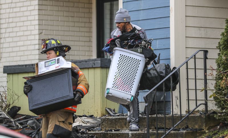 A firefighter helps a resident remove belongings from his burned out home at The Park on Windy Hill Apartments in January 2021. Salt Lake City-based Bridge Investment Group acquired this Marietta complex and three other suburban Atlanta properties since 2019 that the Journal-Constitution found to be persistently dangerous. (John Spink / John.Spink@ajc.com)