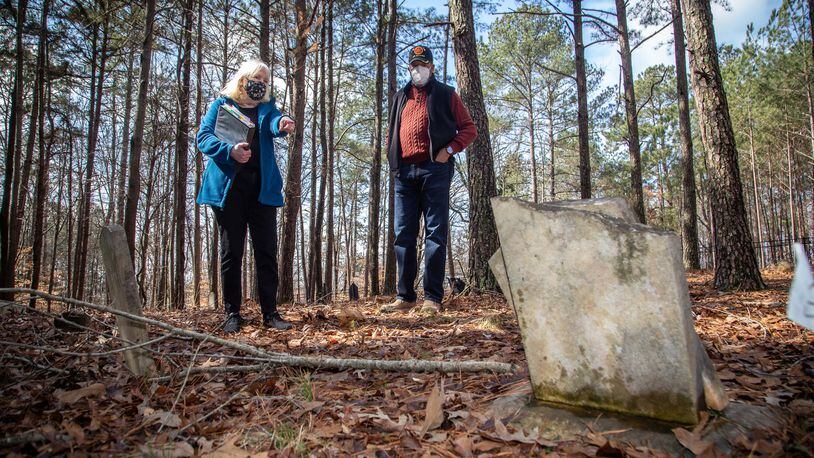 Johns Creek's Historical Society president Joan Compton (L) and Johns Creek's Historical Society Board Member Kirk Canaday look over a headstone at the Macedonia Cemetery in 2021. Johns Creek is might form a nonprofit that would provide guidance in the restoration and preservation of a cemetery where former enslaved people and their relatives are buried. STEVE SCHAEFER FOR THE ATLANTA JOURNAL-CONSTITUTION