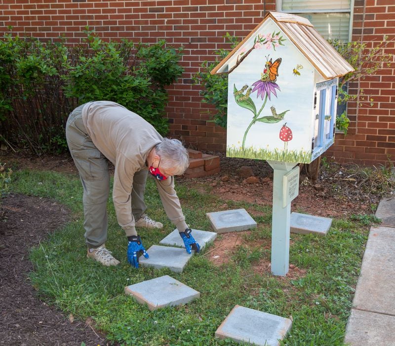 Co-chair Carolyn Chandler places stepping stones around a lending library in the new garden area in front of Avondale Elementary School which also features hand-painted totem poles. The Avondale Estates Garden Club and the Avon Garden Club worked together on the project.
PHIL SKINNER FOR THE ATLANTA JOURNAL-CONSTITUTION.
