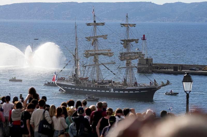 Crowds watch as the Belem, the three-masted sailing ship bringing the Olympic flame from Greece, enters the Old Port in Marseille, southern France, Wednesday, May 8, 2024. After leaving Marseille, a vast relay route is undertaken before the torch odyssey ends on July 27 in Paris. The Paris 2024 Olympic Games will run from July 26 to Aug.11, 2024. (AP Photo/Laurent Cipriani)
