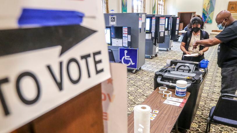 June 21, 2022 Atlanta: With a light morning voter turnout, C. Harper (left) turns in her ballot to poll worker, Michael Bacon (right) at Saint Luke’s Episcopal Church at 435 Peachtree St NE, Atlanta on Tuesday, June 21, 2022.  (John Spink / John.Spink@ajc.com)