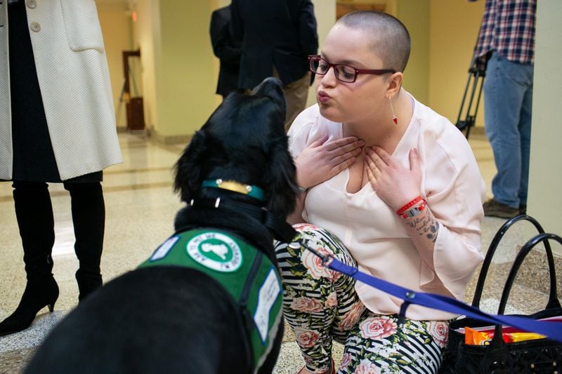 Hailie Massey, 21, plays with her therapy dog, Eleanor, at the Georgia Capitol on Thursday. Massey has a congenital heart defect and has developed thyroid problems, an iron deficiency and a spinal tumor. REBECCA WRIGHT / FOR THE AJC