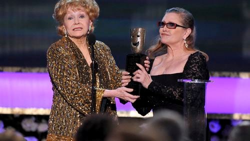 FILE- In this Jan. 25, 2015, file photo, Carrie Fisher, right, presents her mother Debbie Reynolds with the Screen Actors Guild life achievement award at the 21st annual Screen Actors Guild Awards at the Shrine Auditorium in Los Angeles. "La La Land" star Ryan Gosling thanked Reynolds at the Palm Springs Film Festival on Monday, Jan. 2, 2017, for serving as an inspiration to the cast and crew of the film. (Photo by Vince Bucci/Invision/AP, File)