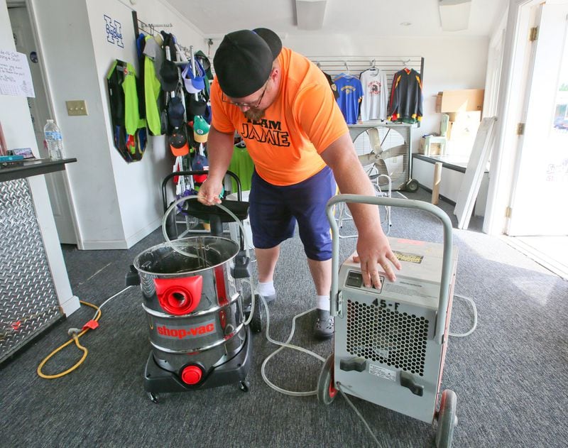 Josh Bowling checks his dehumidifier as he cleans up after flooding at Sign Addiction, owned by his wife Jamie, on Main St. in Hamilton, Friday, June 3, 2016. GREG LYNCH / STAFF