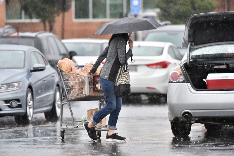 A woman hurries to her car as showers spread over metro Atlanta. (HYOSUB SHIN/HYOSUB.SHIN@AJC.COM)