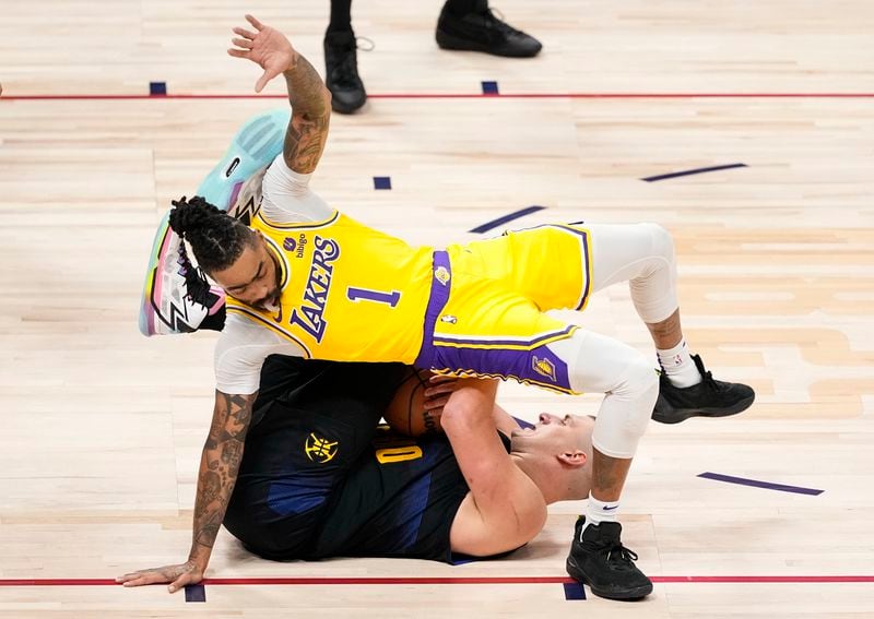 Los Angeles Lakers guard D'Angelo Russell (1) falls on Denver Nuggets center Nikola Jokic, bottom, during the first half in Game 2 of an NBA basketball first-round playoff series Monday, April 22, 2024, in Denver. (AP Photo/Jack Dempsey)