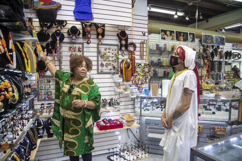 Afro-Centric Network employee Lula Williams, left, helps customer Amira Shade find jewelry during a visit to the store in Atlanta’s West End community, Wednesday, August 25, 2021. (Alyssa Pointer/Atlanta Journal Constitution)
