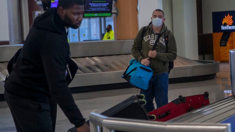 04/28/2020 - Atlanta, Georgia  - A passenger wearing a mask (right) waits as a baggage agent confirms his luggage (left) at the North baggage claim at Atlanta's Hartsfield-Jackson International Airport, Tuesday, April 28, 2020. (ALYSSA POINTER / ALYSSA.POINTER@AJC.COM)