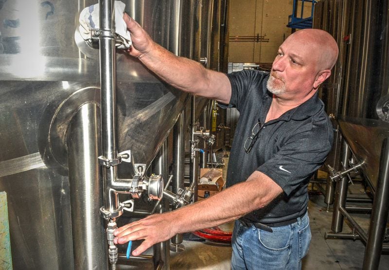 John J.R. Roberts, brewmaster at Bold Monk Brewing Co., dust the tanks in the brewery.