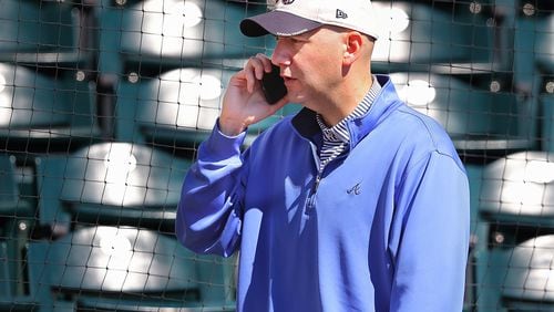 Braves general manager John Coppolella works the phone while watching the team’s spring-training workout. (Curtis Compton/ccompton@ajc.com)