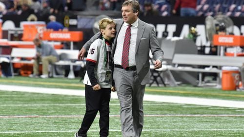Georgia's coach Kirby Smart hugs his son his son Andrew as he walks on the football field before the 2022 College Football Playoff National Championship Game against Alabama at Lucas Oil Stadium in Indianapolis on Monday, January 10, 2022. (Hyosub Shin / Hyosub.Shin@ajc.com)