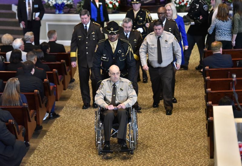 Henry County Deputy Ralph Sidwell "Sid" Callaway, who was wounded in the gunfire, sits in wheelchair during the funeral service.