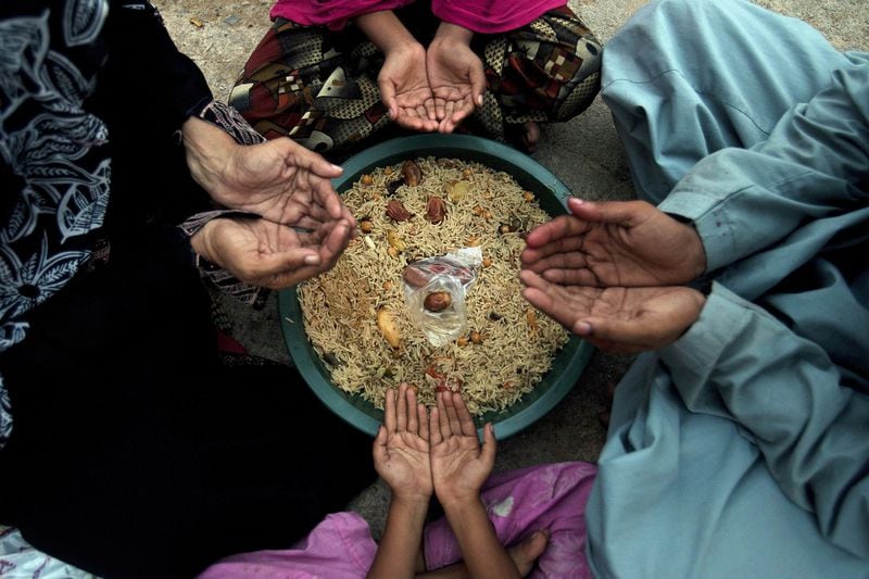 A family prays before breaking its fast during the Islamic holy month of Ramadan at a free food distribution point in Karachi, Pakistan, in 2016. Muslims across the world are observing the holy fasting month of Ramadan, when they refrain from eating, drinking and smoking from dawn to dusk. AP PHOTO / SHAKIL ADIL