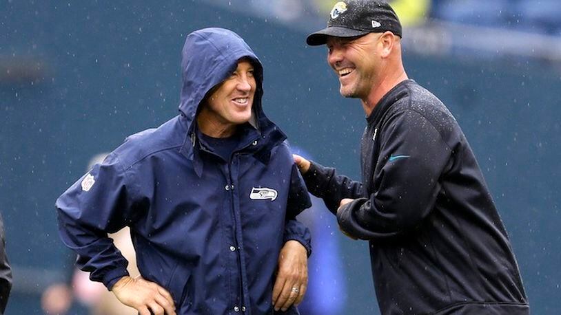 In this Sept. 22, 2013, file photo, Seattle Seahawks head coach Pete Carroll, left, and Jacksonville Jaguars head coach Gus Bradley talk in the rain before an NFL football game in Seattle. The scheme that carried the Seahawks to consecutive Super Bowls (2013-14) has become increasingly popular around the league. It helped Atlanta get to the big game last year and was the catalyst for Jacksonville's stunning turnaround this season. (AP Photo/Ted S. Warren, File)