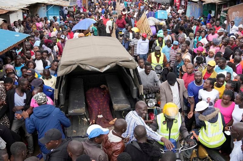 FILE - Residents gather around the covered dead body of a woman found in a house after heavy rain in the Mathare area of Nairobi, Kenya, April 24, 2024. (AP Photo/Brian Inganga)