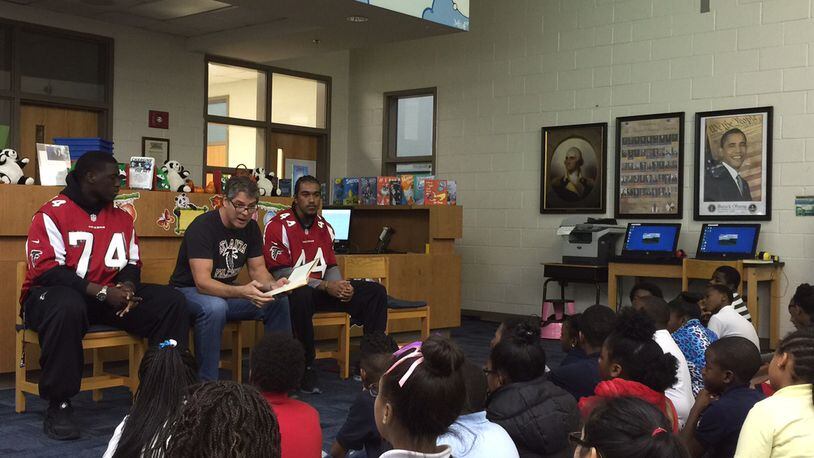 Former Atlanta Falcons defensive end Tim Green, center, flanked by current players Joey Mbu, left, and Vic Beasley Jr., reads to students at Parkside Elementary in Atlanta. MARLON A. WALKER/marlon.walker@ajc.com