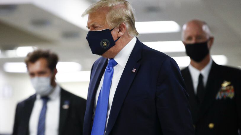 President Donald Trump wears a mask Saturday as he walks down the hallway during his visit to Walter Reed National Military Medical Center in Bethesda, Md. (AP Photo/Patrick Semansky)