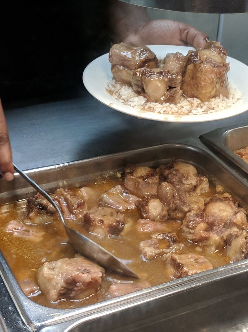 Oxtails with pan juices over rice are a highlight at cafeteria-style Q’s Restaurant. LIGAYA FIGUERAS / LFIGUERAS@AJC.COM