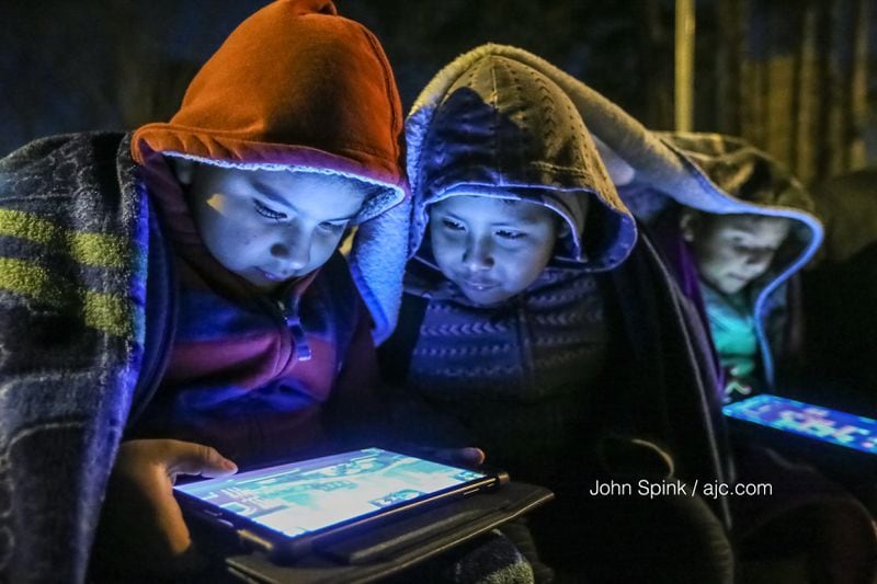 David Lozano (from left), Brandon Martinez and Kimberlyn Lozano bundled up while waiting for their school bus on Buford Highway early Thursday. JOHN SPINK / JSPINK@AJC.COM