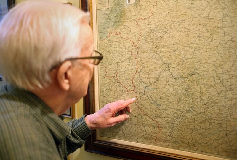 Eddie Sessions looks at the town of Metz on a framed map of France at his home in Carrolton.
