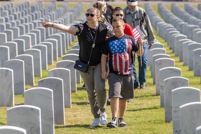 People look for an area to place flags at the Georgia National Cemetery in Canton Saturday, May 27, 2023. Volunteers will place an estimated 21,000 flags by tombstones during the ceremony.  (Steve Schaefer/steve.schaefer@ajc.com)