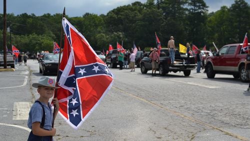 A young Confederate flag supporter stands in the Yellow Daisy parking lot at Stone Mountain Park as more caravans stream in. DANIEL FUNKE / DANIEL.FUNKE@COXINC.COM