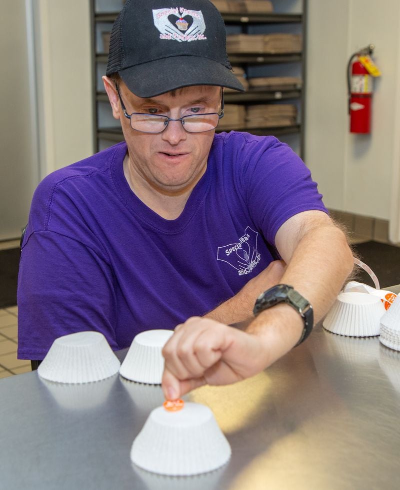 Aaron Clayton places stickers on cupcake paper at Special Kneads and Treats, a bakery in Lawrenceville that employs only special needs individuals. The bakery is on a mission to raise $100,000 in six months. They were given the challenge this spring by a local benefactor who said if they raise that much, he will match the $100k, allowing Tempa and Michael Kohler (the owners) to pay off the shop's mortgage. PHIL SKINNER FOR THE ATLANTA JOURNAL-CONSTITUTION.