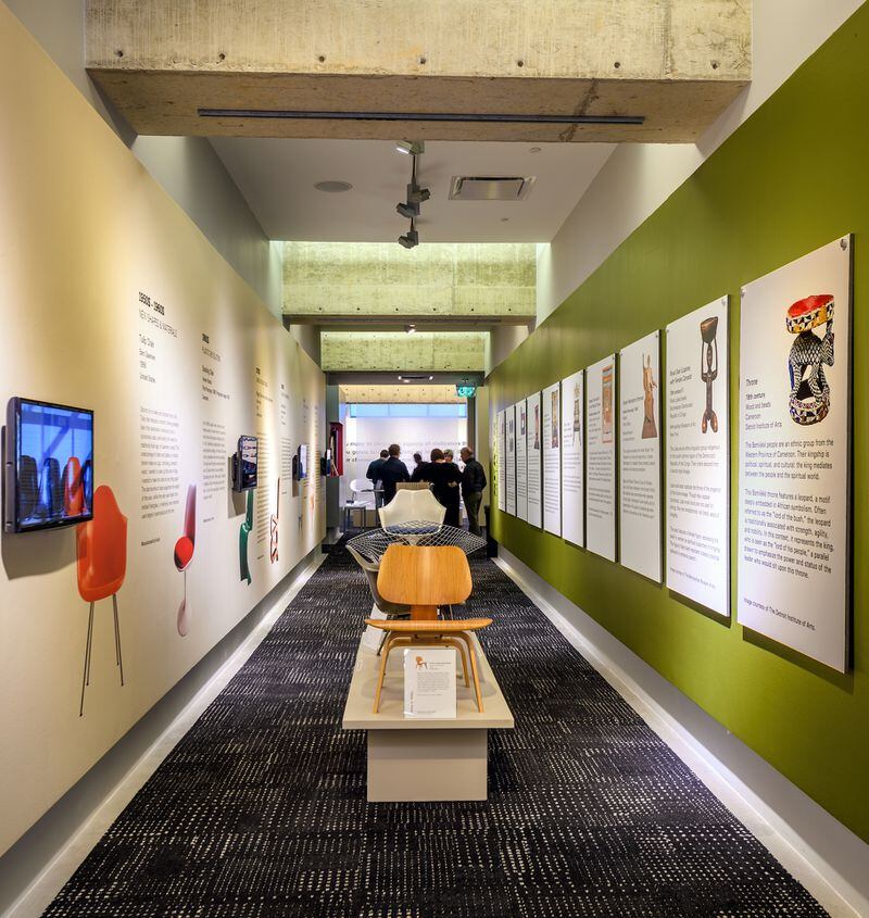 On the left wall, MODA's exhibition hallway provides an illustrated primer on iconic chair design of the last 150 years. On the right: photos and text that explores seating designed for those in power.