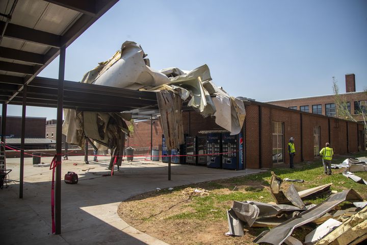 Workmen survey the damage to the outside of Newnan High School. (Alyssa Pointer / Alyssa.Pointer@ajc.com)