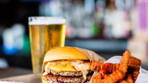The meat-substitute Impossible Burger, Dixie Style, with sweet potato fries and a beer at Grindhouse Kiiller Burgers on Memorial Drive. Dixie Style means it comes with pimento cheese, fried green tomato, Carolina coleslaw, and chipotle ranch. CONTRIBUTED BY HENRI HOLLIS