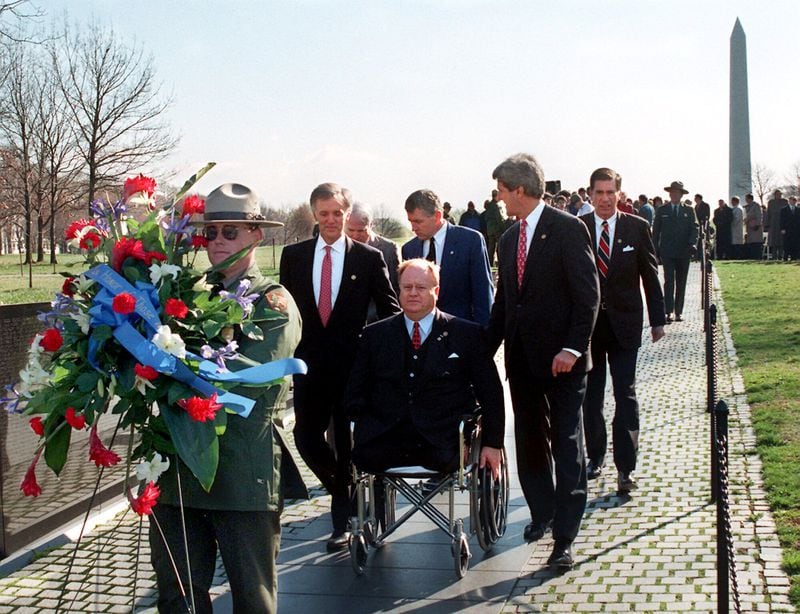 In this file photo, then-U.S. Sen. Max Cleland, D-Ga. (in wheelchair), and fellow senators — (left to right) Bob Kerrey, D-Neb.; John McCain, R-Ariz.; Charles Hagel, R-Neb.; John Kerry, D-Mass.; and Chuck Robb, D-Va. — walk along the Vietnam Veterans Memorial wall behind the wreath they would lay to commemorate the 15th anniversary of groundbreaking for the memorial. All six senators served in Vietnam, and Cleland lost both legs and an arm in that war. He was awarded the Silver Star, the Bronze Star, and the Soldier’s Medal. He appears briefly in the introduction of the documentary series. (Photo by Rick McKay/Washington Bureau)