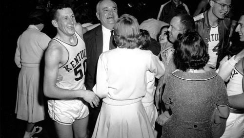 Kentucky basketball coach Adolph Rupp and guard Ad Smith (50) face fans and cheerleaders after Kentucky won their fourth NCAA championship over Seattle in Louisville, Ky., on March 22, 1958. (AP Photo/File)
