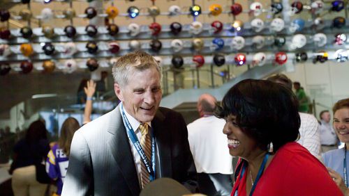 Former Georgia Tech, Alabama, Kentucky and Georgia State football coach, Bill Curry, left, greets visitors at the College Football Hall of Fame grand opening, Saturday, Aug. 23, 2014, in Atlanta. The new high-tech hall features an interactive experience that begins when the guest registers for a smart pass, selects a favorite school and then sees that school's helmet illuminated. (AP Photo/David Goldman)