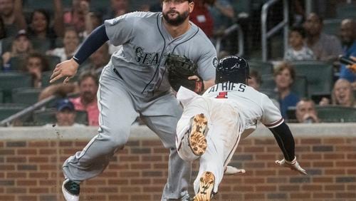 Atlanta Braves second baseman Ozzie Albies dives to home plate to score as Seattle Mariners first baseman Yonder Alonso waits for the throw after a rundown on the third base line during the sixth inning of a baseball game, Tuesday, Aug. 22, 2017, in Atlanta. (AP Photo/John Amis)