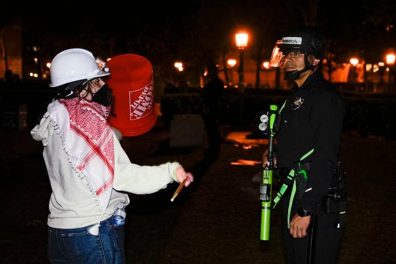 A person protests in front of a police officer after police arrived on the campus at the University of Southern California to clear an encampment set up by pro-Palestinian demonstrators Sunday, May 5, 2024, in Los Angeles. (AP Photo/Ryan Sun)