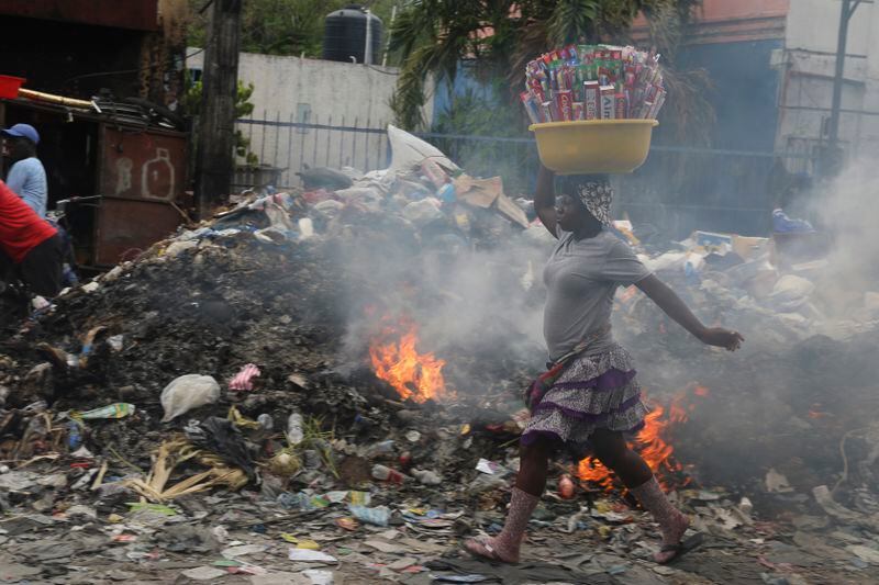 A street vendor walks past a pile of burning trash, in Port-au-Prince, Haiti, Tuesday, April 30, 2024. (AP Photo/Odelyn Joseph)