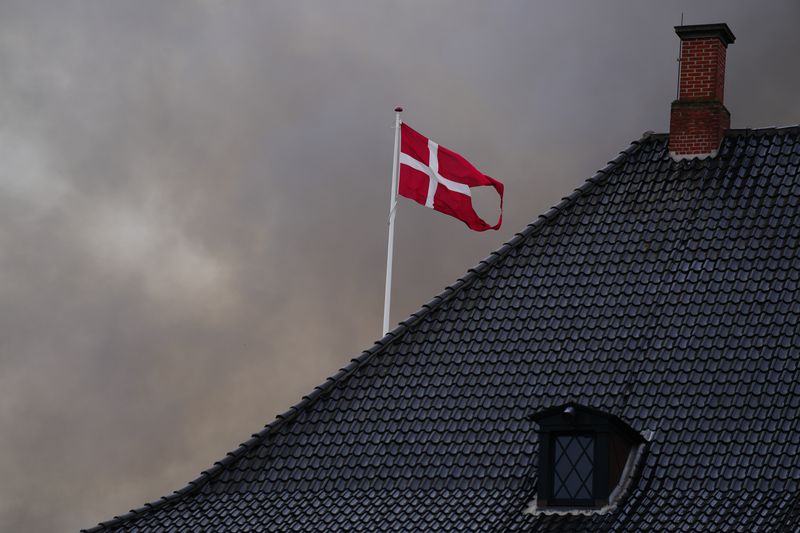 Smoke surrounds the Danish flag above the Ministry of Finance as the Old Stock Exchange, not in the picture, burns, in Copenhagen, Denmark, Tuesday, April 16, 2024. (Ida Marie Odgaard/Ritzau Scanpix via AP)