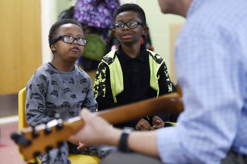 Roy Joyner plays a guitar while Ashton Hall, 9, right, and Tony Coleman, 9, left, listen intently during a music therapy session at Campbell Elementary School in Fairburn. Joyner works in several schools to help special-needs children through music therapy. (DAVID BARNES / SPECIAL)