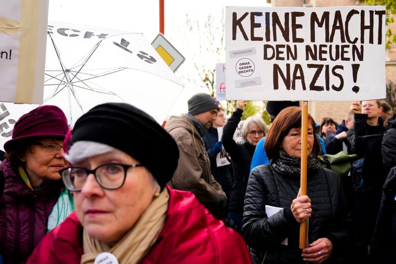 A protestor holds a poster reading 'No power for the new Nazis! ' outside the state court in Halle, Germany, Thursday, April 18, 2024. Bjoern Hoecke, goes on trial at the state court in Halle on charges related to his alleged use in a 2021 speech of a slogan used by the Nazis' SA stormtroopers. (AP Photo/Ebrahim Noroozi, Pool)