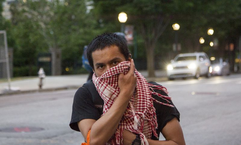 Micha Chishtia, a member of International Socialist Atlanta, holds a scarf to his face at the emergency protest for the violence in Gaza in Downtown Atlanta, Georgia, on Tuesday, May 15, 2018. (REANN HUBER/REANN.HUBER@AJC.COM)
