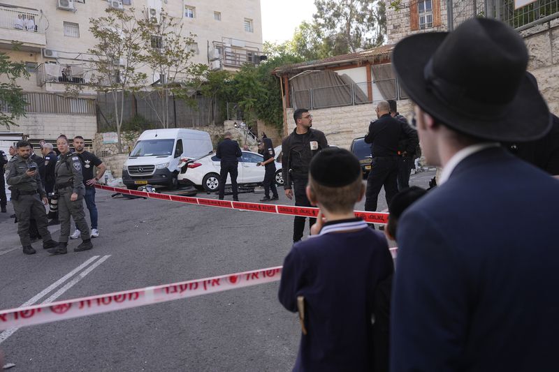Ultra-Orthodox Jewish residents watch Israeli police work at the scene of a suspected ramming attack that wounded three people on the eve of the Jewish holiday of Passover, in Jerusalem, Monday, April 22, 2024. Israeli police say a car slammed into pedestrians in Jerusalem on Monday, wounding three people lightly in an apparent attack. (AP Photo/Ohad Zwigenberg)