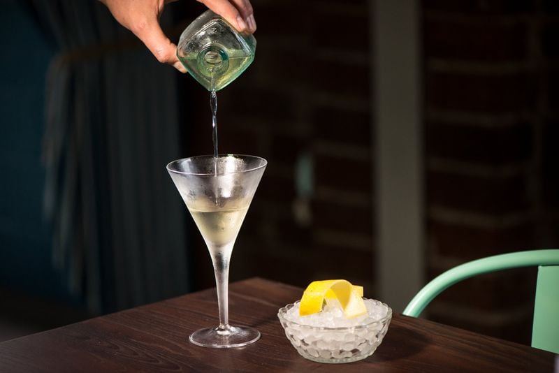The Watchman bottled martini with lemon, olive and pineapple garnish on the side.