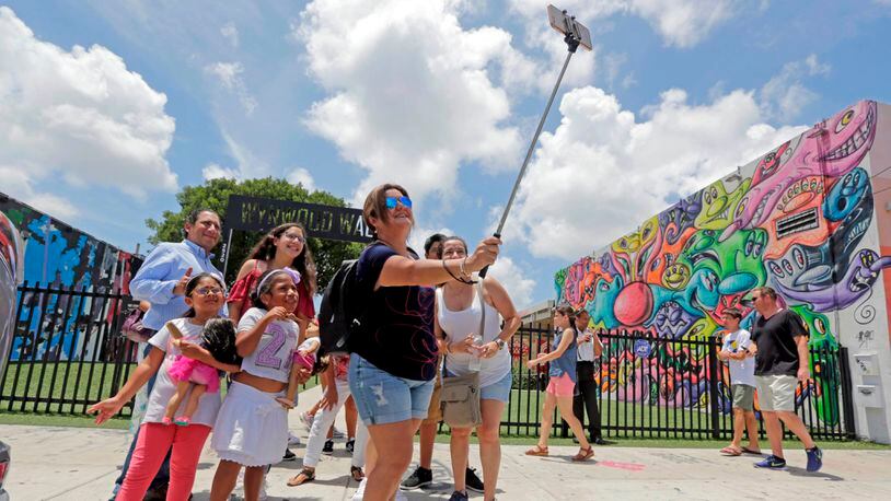 In this Friday, Aug. 5, 2016, file photo, a family from Peru takes a selfie in front of the Wynwood Walls, in the Wynwood area of Miami. The recent announcement that more than a dozen people have been infected with Zika by mosquitoes in the area has scared away some, but many others are still coming. The American Southwest, New England and Bermuda are providing a virus-free alternative, but destinations are hesitant to market themselves as such. (AP Photo/Alan Diaz, File)