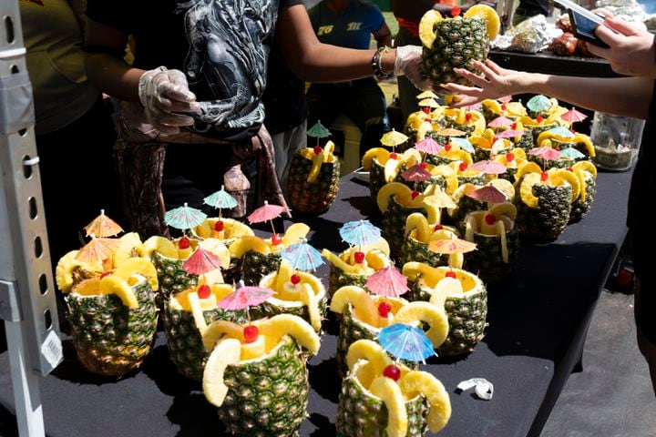 Amarah Geiger buys a pineapple filled with piña colada while attending the Dogwood Festival in Piedmont Park on Saturday, April 13, 2024.   (Ben Gray / Ben@BenGray.com)