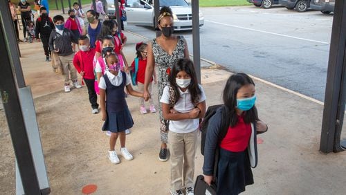 Parents and their children line up to enter Lake City Elementary in Morrow on the first day of school, Monday, August 2, 2021. Clayton County school district is requiring masks for staff and students this school year. STEVE SCHAEFER FOR THE ATLANTA JOURNAL-CONSTITUTION